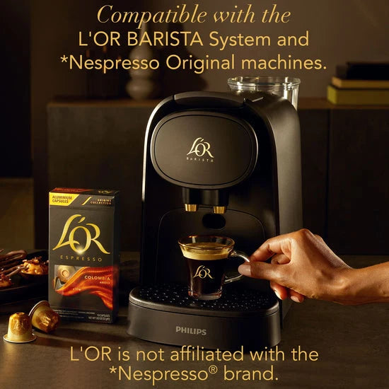 Philips L'OR Barista coffee machine with a hand holding a glass of coffee, surrounded by L'OR coffee packaging.