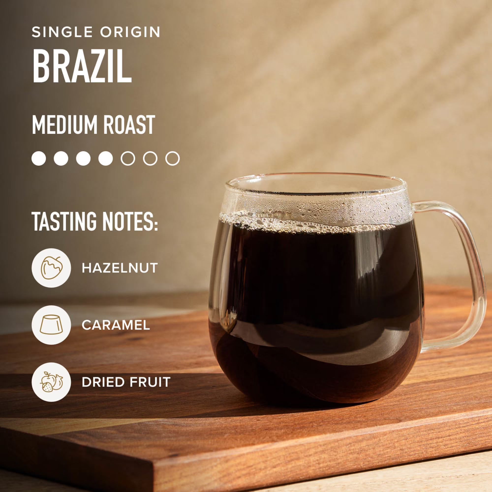 Glass mug of coffee with single origin Brazil information on a wooden surface